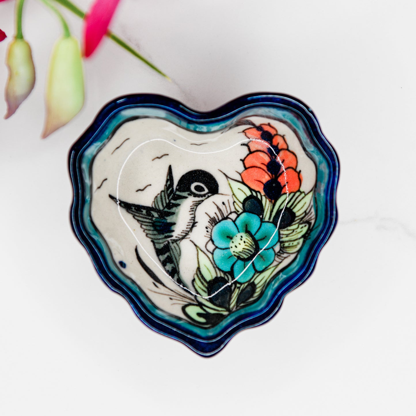 Heart-shaped ceramic dish with floral and bird design on a white background