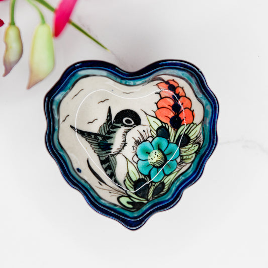 Heart-shaped ceramic dish with floral and bird design on a white background